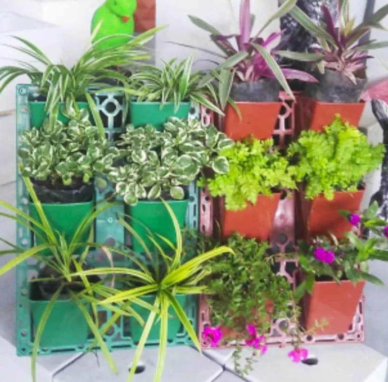 Recycled plastic vertical wall planters in green and terracotta, planted with flowers and foliage